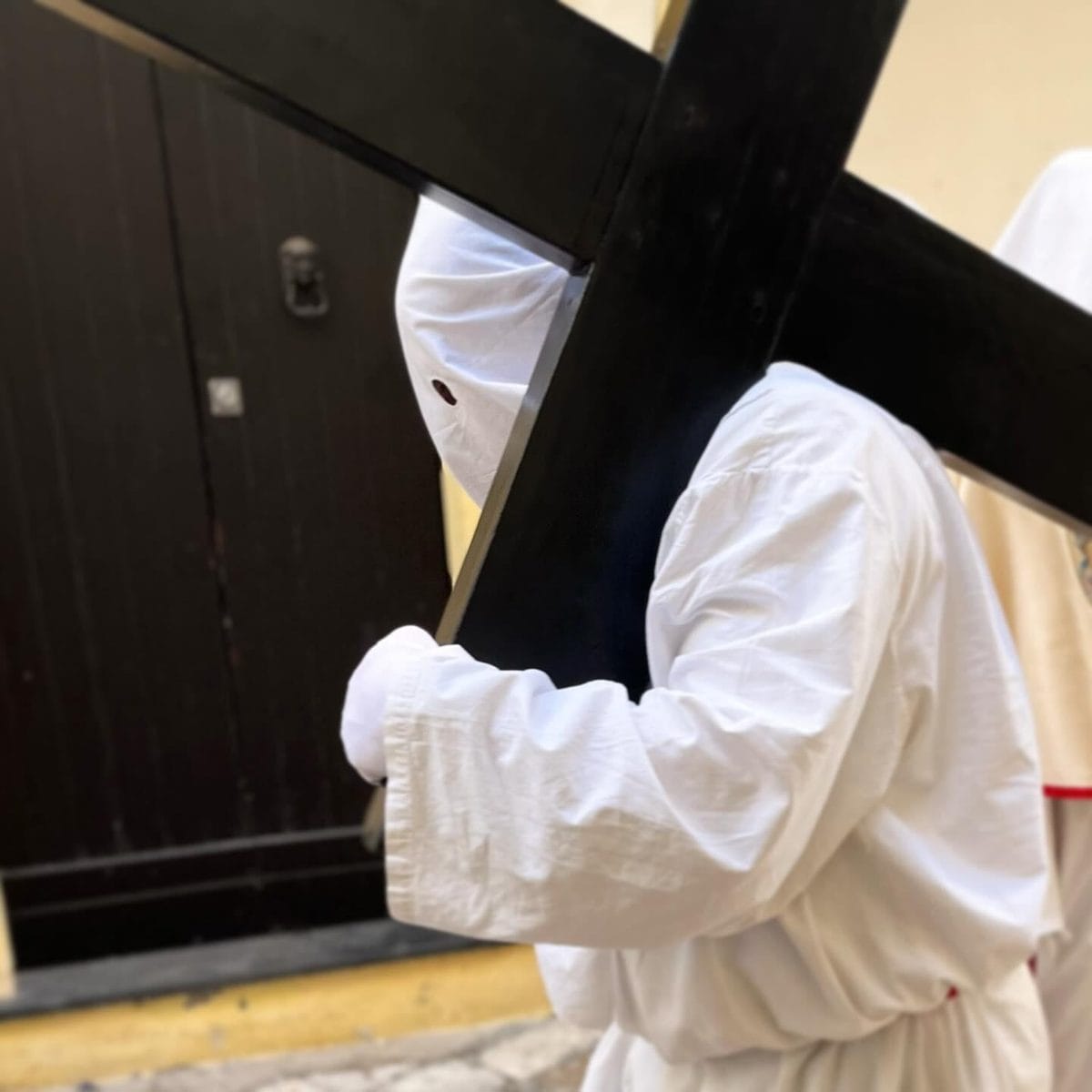 Penitente incappucciato porta una pesante croce durante la processione della Settimana Santa a Gallipoli